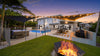 String lights attached to a shade sail with Koru Clips above a modern backyard pool and patio at dusk.